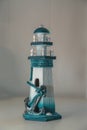 A figurine in the form of a lighthouse with a large anchor in the foreground. Blurred background Royalty Free Stock Photo