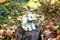 Figurine of a gray baby elephant in the garden on a path with yellow leaves