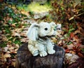 figurine of a gray baby elephant in the garden on a path with yellow leaves