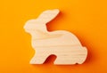 A figurine of a hare or a rabbit carved from solid pine by a hand jigsaw. On a yellow background