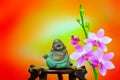 Figurine of laughing buddha decorated with pink orchid flowers Royalty Free Stock Photo