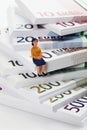 Figurine pensioner sitting on bundles of euro notes