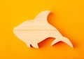 Figurine of a shark carved from solid pine by hand jigsaw. On a yellow background