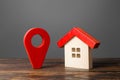 Figurine wooden house and red location pointer. Nice neighborhood. Infrastructure and utilities. Location and surroundings Royalty Free Stock Photo