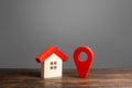 Figurine wooden house and red location pointer. Location and surroundings of the building. Moving in another home