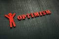 Figurine and word optimism on the dark surface. Royalty Free Stock Photo