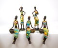 Figurines of ceramics. African American women painted in bright national outfits sitting standing on a white background.