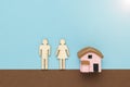 Figurines of a man and a woman near a figurine of a house on a brown and blue background