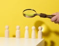 Figurines of men on a white table and magnifying glass. Concept of searching for employees in the company, recruiting personnel, Royalty Free Stock Photo