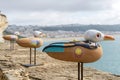 Figurines of seagulls with the image of Jacques-Yves Cousteau on the wall of the fortress in Nazare close up