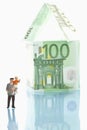 Figurines standing in front of house of 100 euro notes Royalty Free Stock Photo