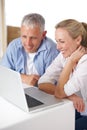 Figuring out the new laptop. A mature couple looking happy as they work on their laptop at home. Royalty Free Stock Photo