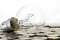 Filament bulb lying on coins Royalty Free Stock Photo