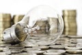 Filament bulb lying on coins Royalty Free Stock Photo