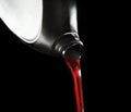 File close up red motor oil pouping from black plastic bottle ag Royalty Free Stock Photo