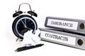 File folders and alarm clock symbolize time pressure while working on contracts and insurance Royalty Free Stock Photo