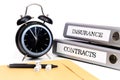 File folders and alarm clock symbolize time pressure while working on contracts and insurance Royalty Free Stock Photo