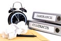 File folders and alarm clock symbolize time pressure while working on contracts and insurance Royalty Free Stock Photo