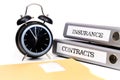 File folders and alarm clock symbolize time pressure while working on contracts and insurance Royalty Free Stock Photo