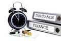 File folders and alarm clock symbolize time pressure while working on finance and insurance
