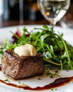 Filet Tenderloin alongside arugula salad with white sauce cream on top, fancy Italian restaurant blurry background