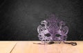 Filigree Mysterious Venetian masquerade mask on wooden table and texture black background