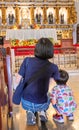 A Filipina woman and her small child,sit on the floor of the aislenext to the altar,at Saint Nino Church