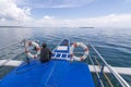 A Filipino boatman rests near the bow of a tourist bangka or outrigger cruising through calm glassy waters in Bohol, Philippines