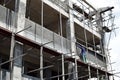 Filipino construction mason plastering grout on board scaffolding pipes on high-rise building alone