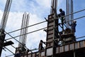 Filipino construction steel-men working joining column steel pieces on board scaffolding pipes on high-rise building