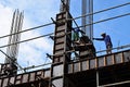 Filipino construction steel-men working joining column steel pieces on board scaffolding pipes on high-rise building