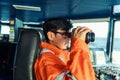 Filipino deck Officer on bridge of vessel or ship looking through binoculars