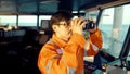 Filipino deck Officer on bridge of vessel or ship looking through binoculars
