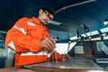 Filipino deck Officer on bridge of vessel or ship. He is plotting position on chart