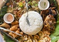 Filipino food on a plate with a banana leaf base. Rice, chicken, lumpia, pansit