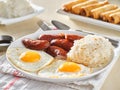 Filipino silog breakfast with garlic fried rice, longsilog, and two sunny side up eggs