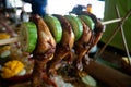 Filipino traditional authentic dish: philippine roasted chicken legs barbecue on a stick with cucumber