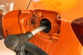 Fill car with fuel in petrol station. Pumping gasoline fuel in orange car at a gas station in city. Close up Royalty Free Stock Photo