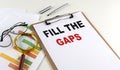 FILL THE GAPS text on clipboard with chart on white background, business concept Royalty Free Stock Photo
