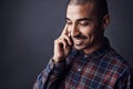 Fill me in on the details. Studio shot of a young man talking on a cellphone against a dark background. Royalty Free Stock Photo