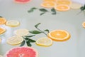 Filled bath with water and slices of citrus orange lemon grapefruit leaves water