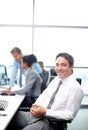 Filled with the confidence it takes to succeed. Positive businessman sitting at his desk with his colleagues working in