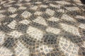 Filled frame background wallpaper of a black, grey and white sett paving surface forming beautiful geometrical shapes and patterns