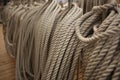 Filled frame background wallpaper photo of rows of beige plaited nautical tow ropes reeled together, hanging in lines on the deck