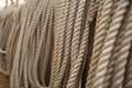 Filled frame background wallpaper photo of rows of beige plaited nautical tow ropes reeled together, hanging in lines on the deck