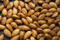 Filled frame background wallpaper shot of a bunch of crunchy roasted almonds with sea salt on a black background