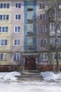 Filled frame full screen shot of an old ugly colorful facade of a soviet block house with windows, balconies and naked birches and