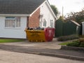Filled up skip rubbish dumpster outside house pavement