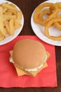 Fillet fish sandwich on red napkin with french fries and onion rings