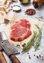 Fillet of raw beef rib eye steak on with meat cleaver,salt and pepper on light table background with tenderizer,pepper mill and Royalty Free Stock Photo